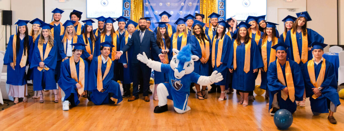 Group photo of some of the American High School Academy graduate of 2023 with the School's mascot, Marvin.